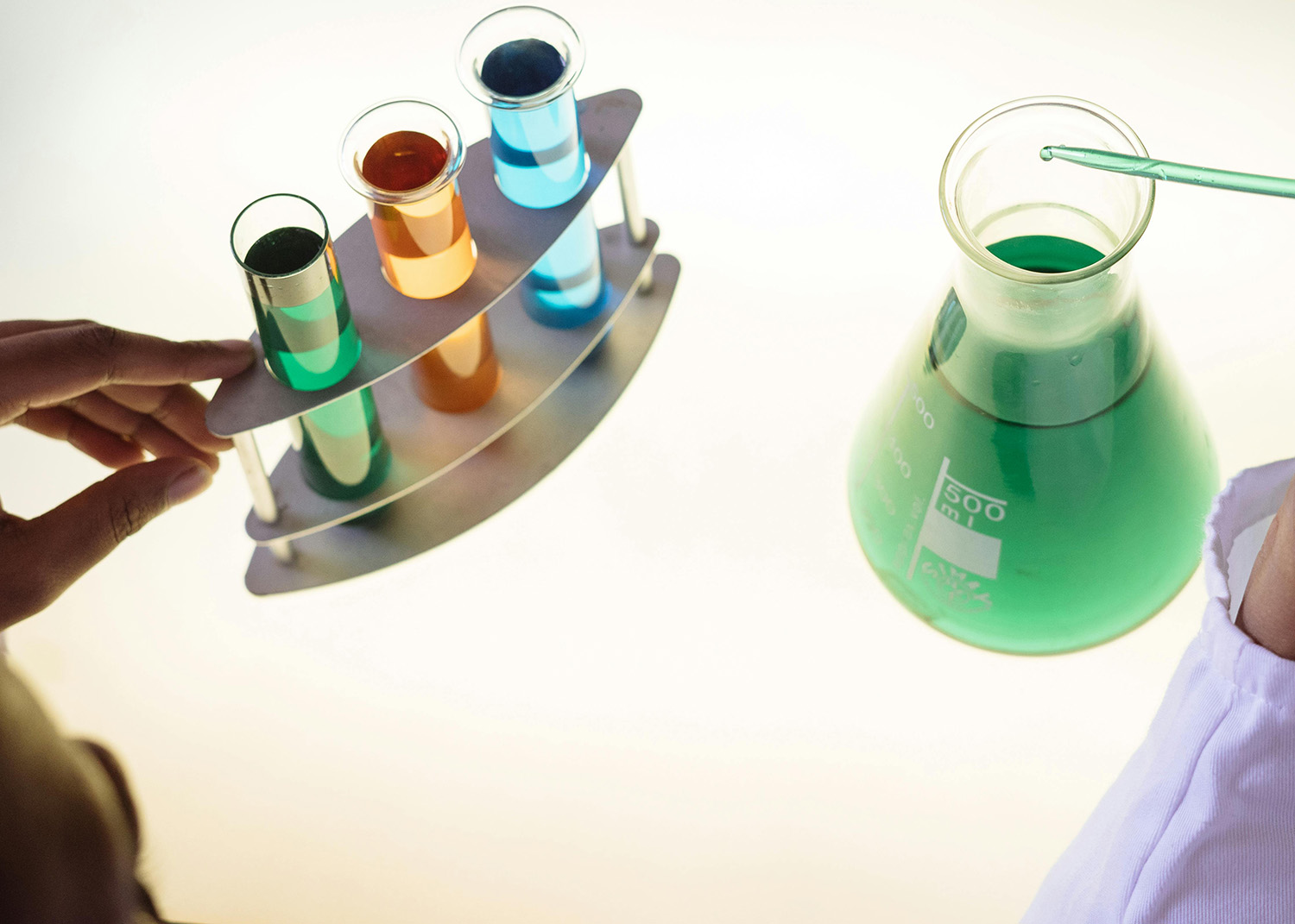 Close-up of liquid chemical additives being poured into a large industrial blending vat