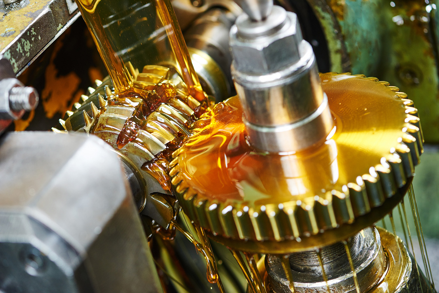 Clear amber lubricant liquid being poured into a glass beaker in a laboratory setting